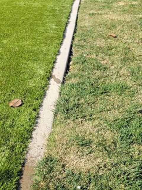 The same lawn after the install: turf laid back along the path, no scar and no bare ground