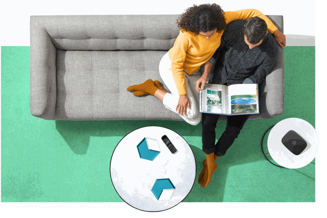 A couple relaxing on a sofa at home with an Ooma phone device nearby